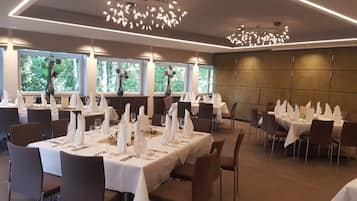 Comedor con mesas dispuestas para el servicio, ventanas amplias y luminarias modernas.