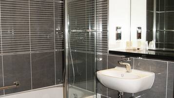 A modern bathroom with a glass-enclosed shower, a white sink, and a toilet.