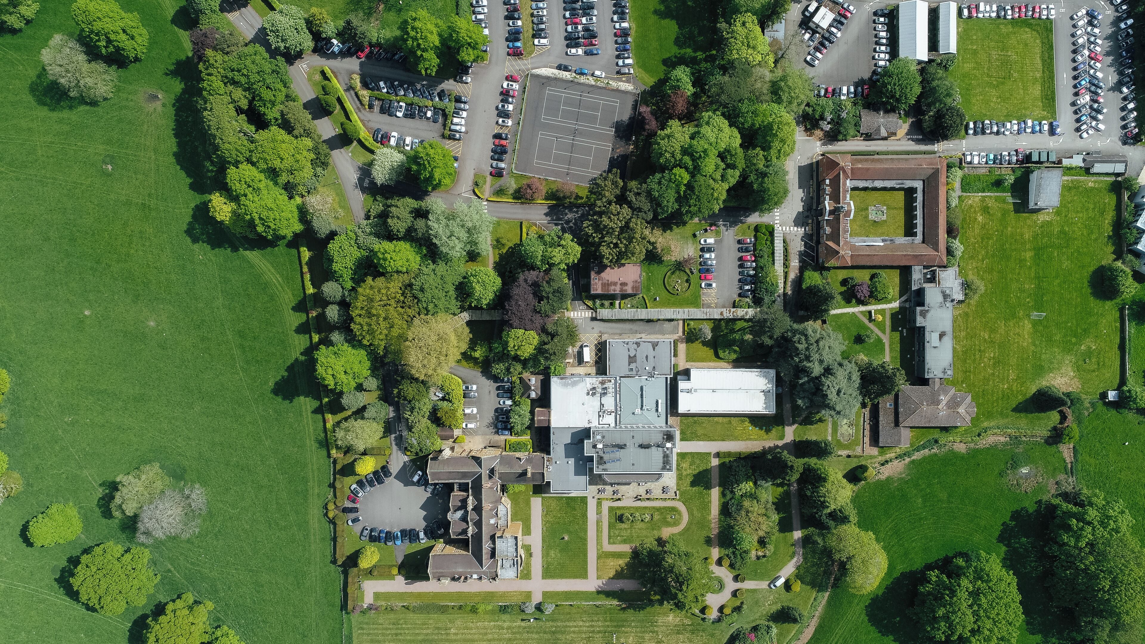 Vista aérea de un campus con varios edificios, zonas de estacionamiento y espacios verdes.
