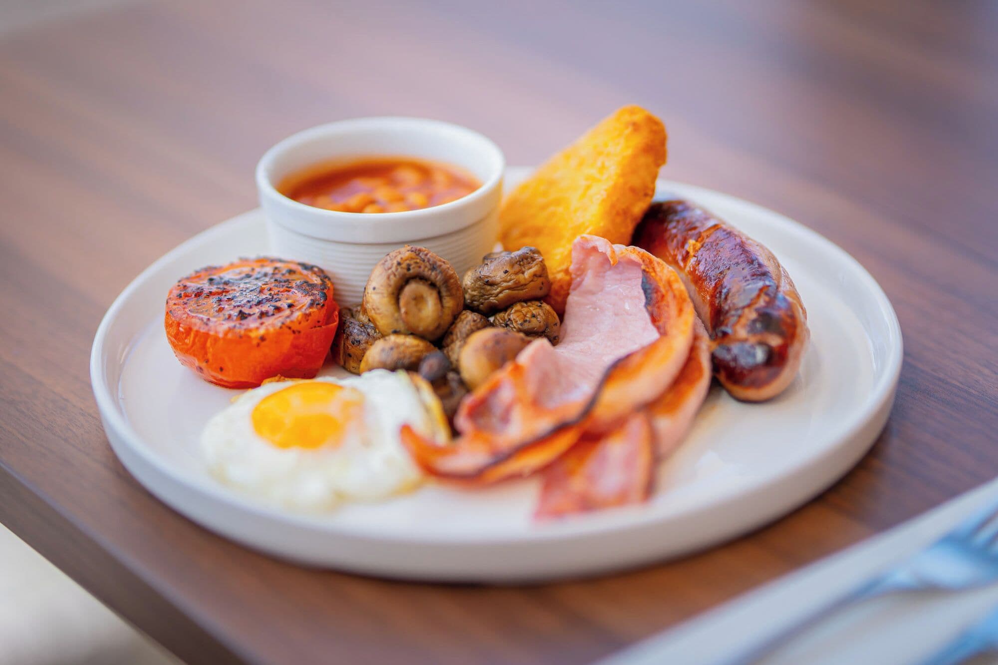 A plate of breakfast food including eggs, bacon, sausages, mushrooms, and toast.