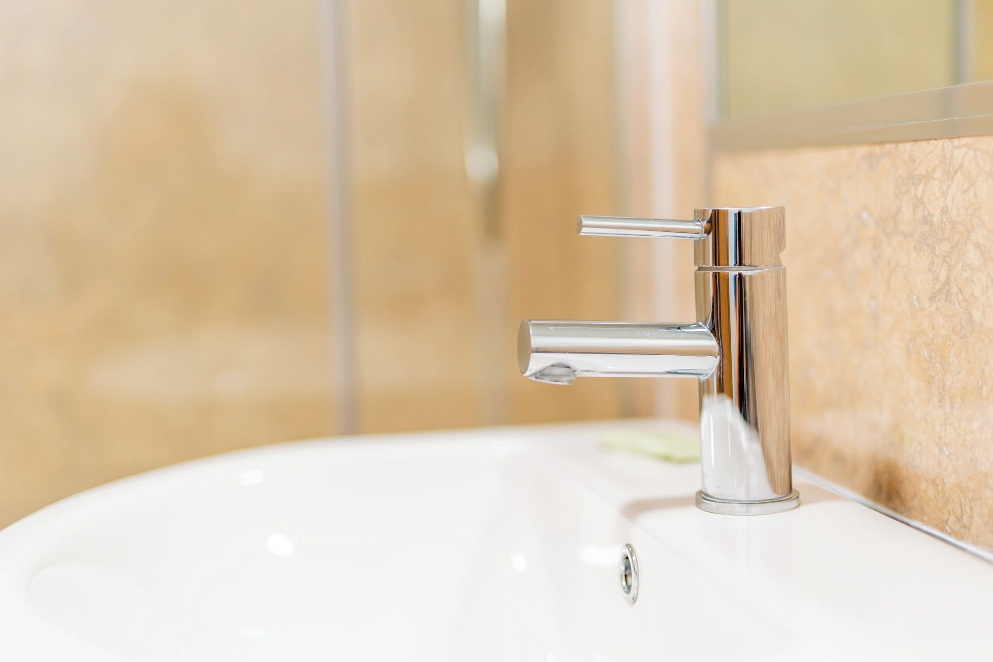 A modern bathroom sink with a chrome faucet and a mirror above it.