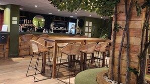 A restaurant with a wooden bar, wicker chairs, and a central seating area with a cushioned bench. - Ashorne Hill Leamington Spa (Royal Leamington Spa)