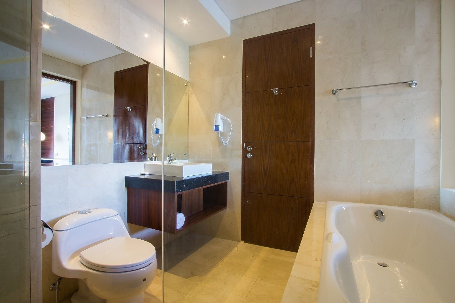 A modern bathroom with a glass shower enclosure, a separate toilet, a vanity with a sink, and a freestanding bathtub.