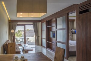 Quarto de hotel moderno com decoração em madeira, televisão de tela plana, sofá, mesa de jantar e varanda com vista para a cidade.
