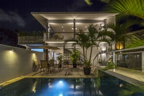 Une maison moderne dotée d’une piscine, d’un espace salon extérieur et d’un balcon.
