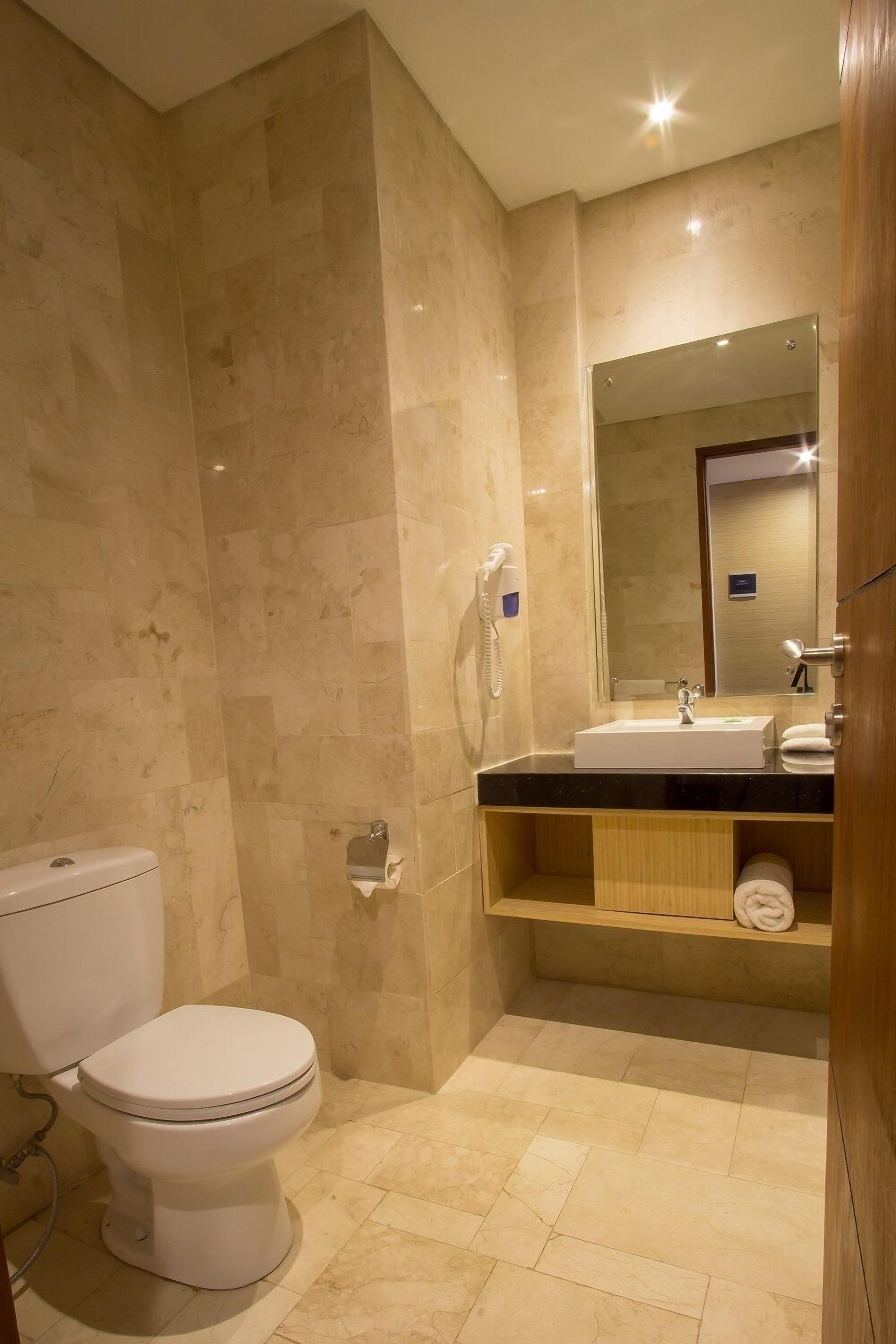 A bathroom with a toilet, sink, mirror, and a towel rack.