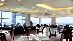 A restaurant with tables set for dining, large windows, and a view of a bridge.