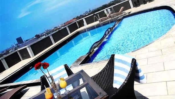 A pool area with lounge chairs and a table with drinks.