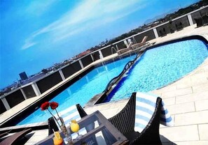 Un área de piscina con sillones de descanso y una mesa con bebidas.
