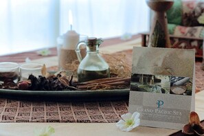 A table with a placemat, a glass pitcher, a candle, and a card with the Grand Pacific Spa logo. - Grand Pacific Hotel (Bandung)