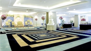 A spacious hall with a stage, chairs, and floral decorations.