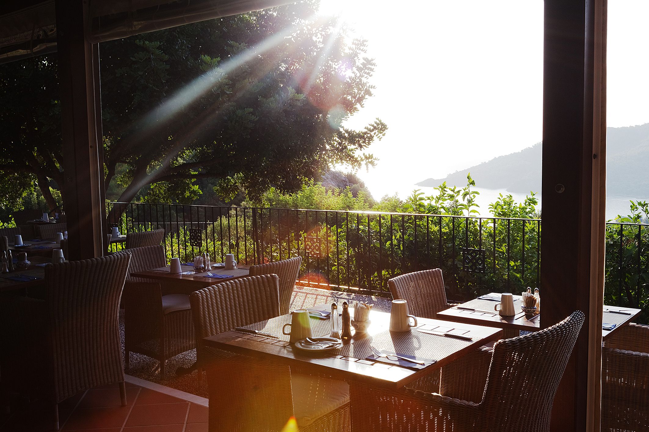 An outdoor dining area with wicker furniture and a view of a mountainous landscape.