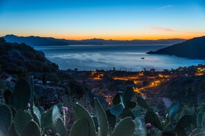 Un paisaje costero con vista al mar, montañas y una ciudad iluminada.