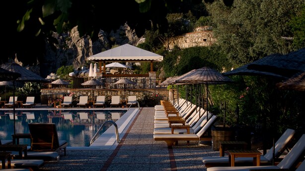 A poolside area with lounge chairs, umbrellas, and a covered seating area. - Dionysos Hotel (Marmaris)