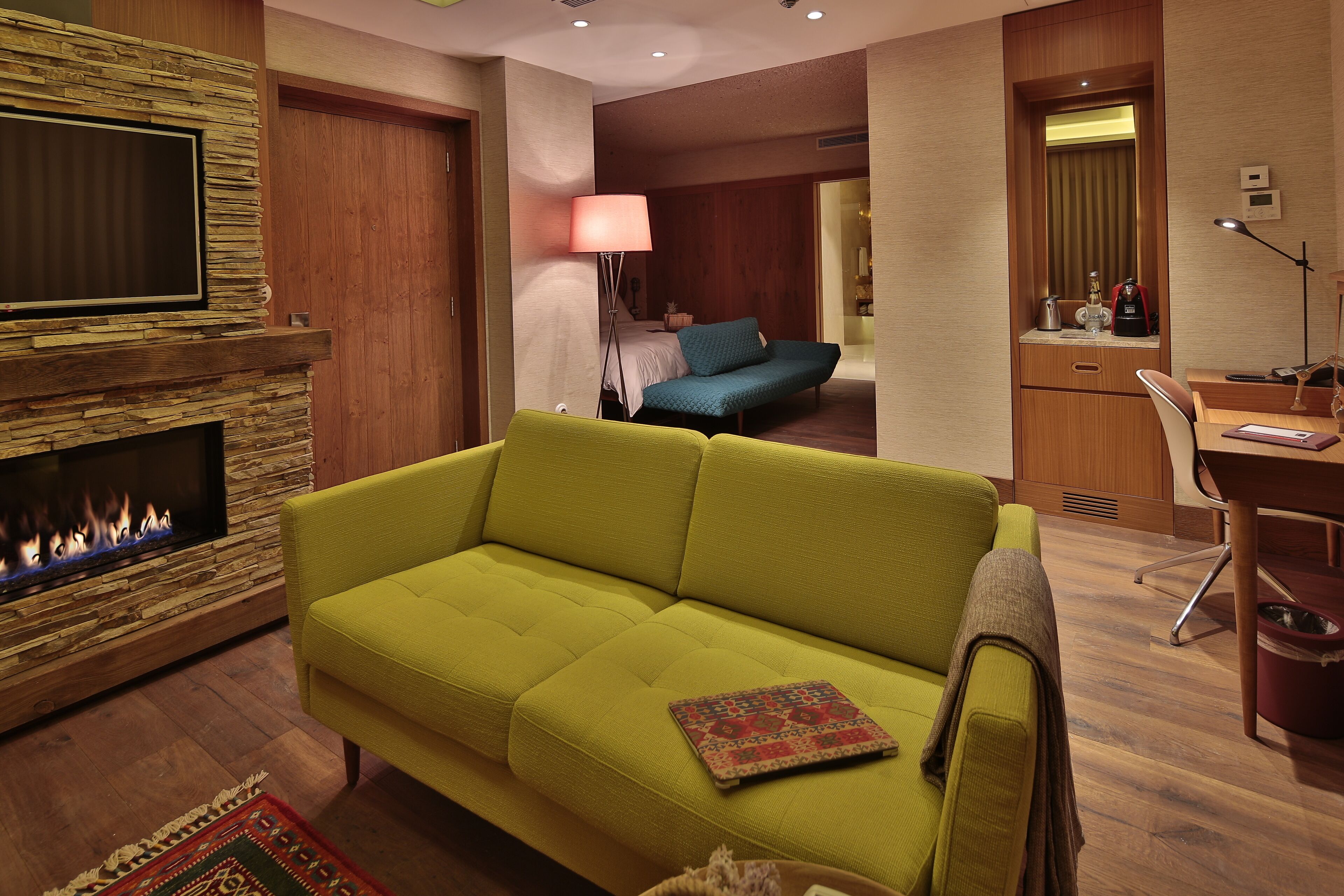 Una sala de estar moderna con un sofá verde, una chimenea y un área de escritorio.