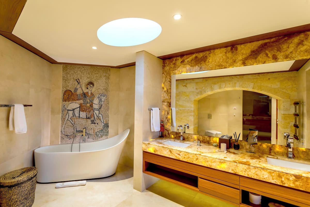 Een moderne badkamer met een vrijstaand bad, een grote spiegel en een marmeren aanrechtblad.