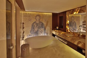 Une salle de bain moderne avec une grande baignoire sur pieds, un meuble-lavabo à deux vasques et un mur décoré de mosaïques.