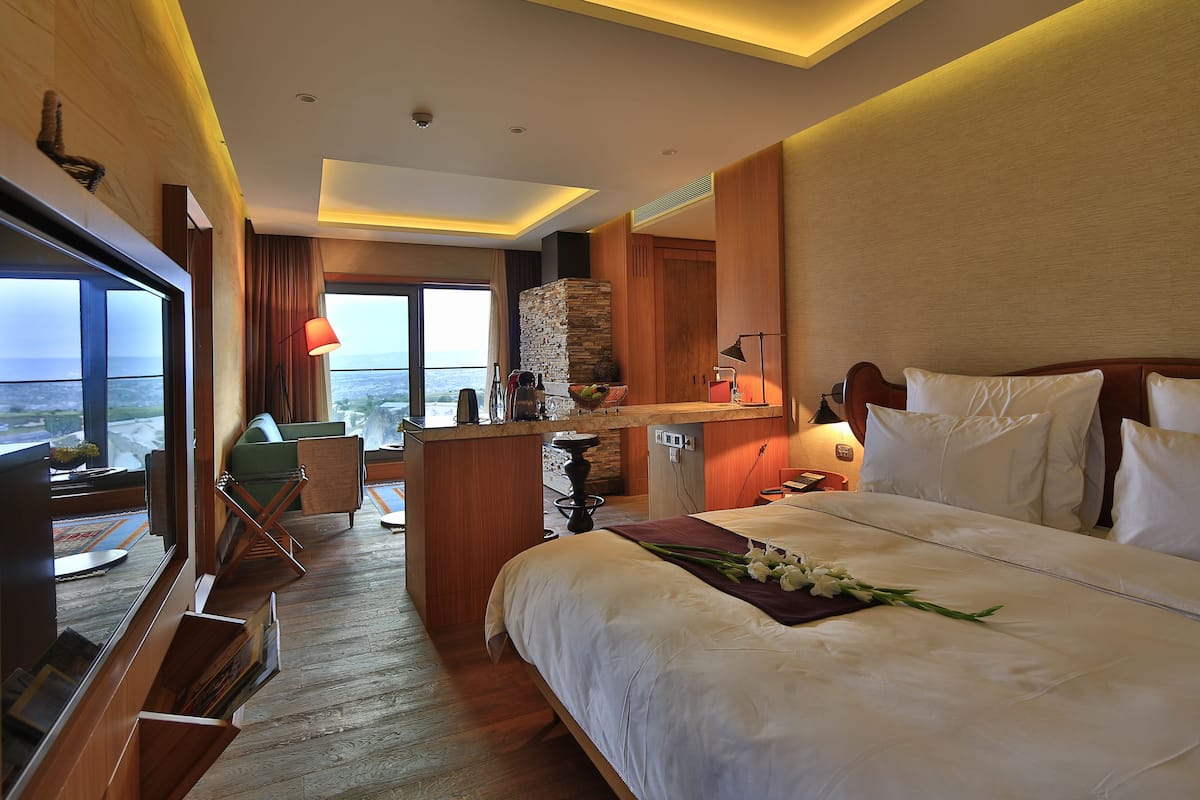 Hotelkamer met een groot bed, een klein bureau, uitzicht op de oceaan en een balkon.