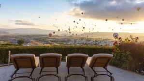 A terrace with three wooden lounge chairs facing a scenic view of a valley with hot air balloons in the sky. - Ariana Sustainable Luxury Lodge - Special Class (Nevsehir)