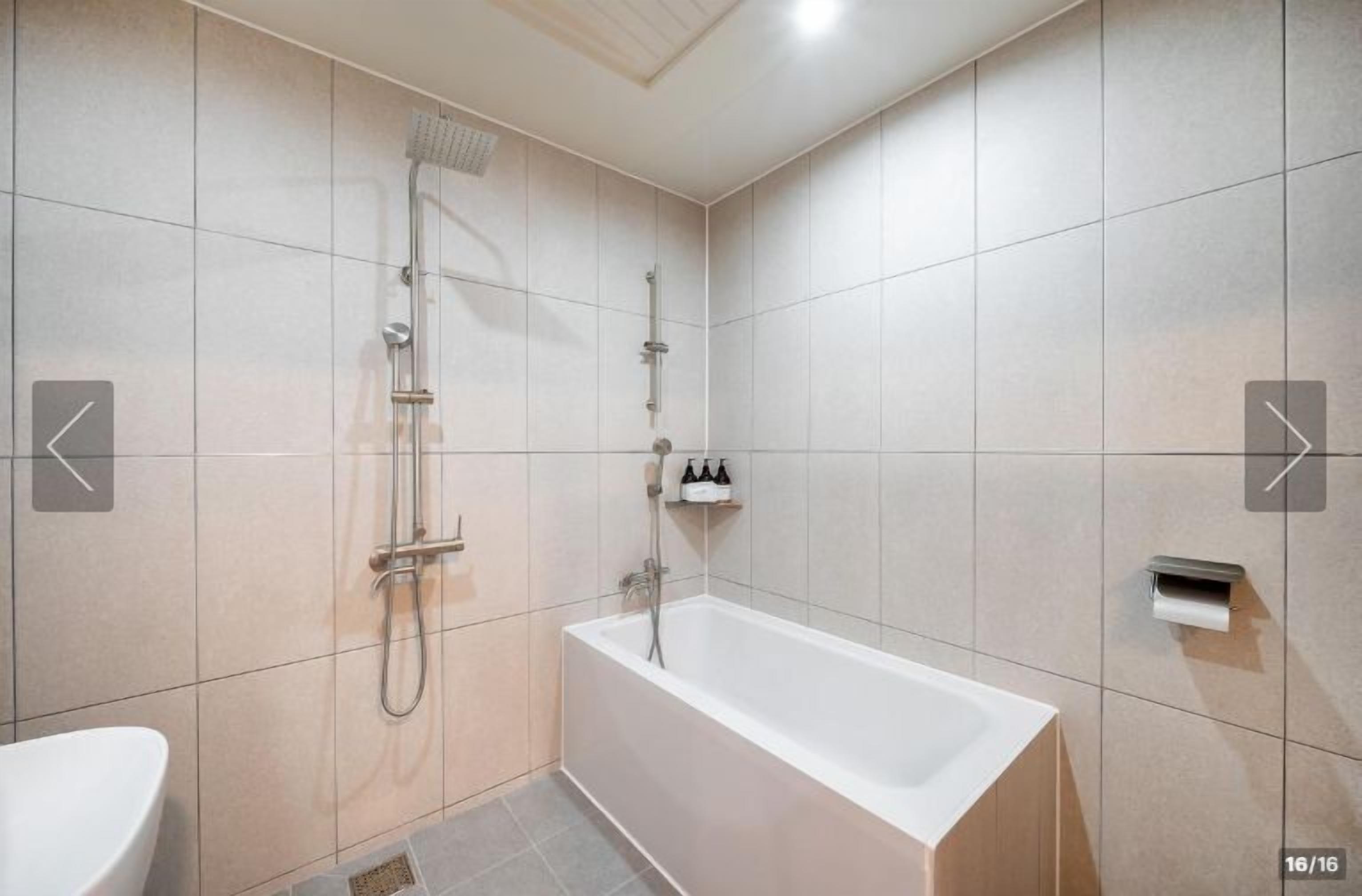 A modern bathroom with a bathtub, shower, and toilet.