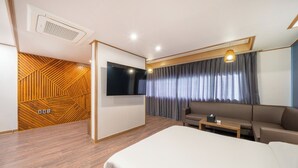Une chambre d’hôtel moderne avec un grand lit, un canapé, une télévision et un mur décoratif en bois.
