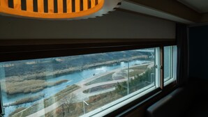 Une pièce dotée d’une grande fenêtre donnant sur une rivière et un pont.
