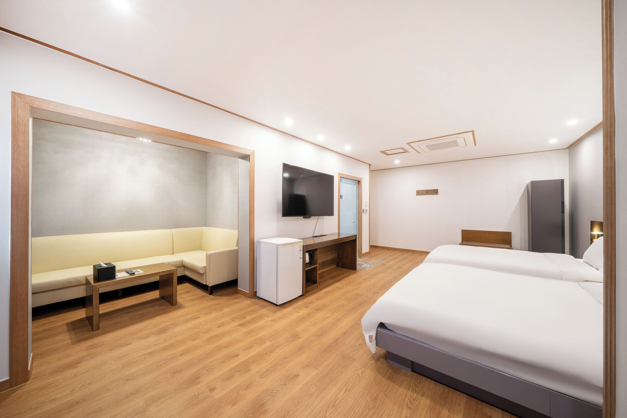 Een moderne hotelkamer met een groot bed, een bank, een bureau met een flatscreen televisie en een kleine koelkast.