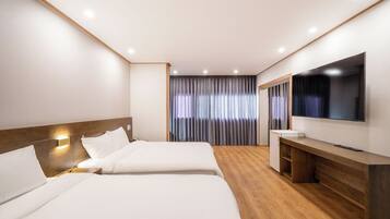 A hotel room with two beds, a TV, a desk, and a window with curtains.