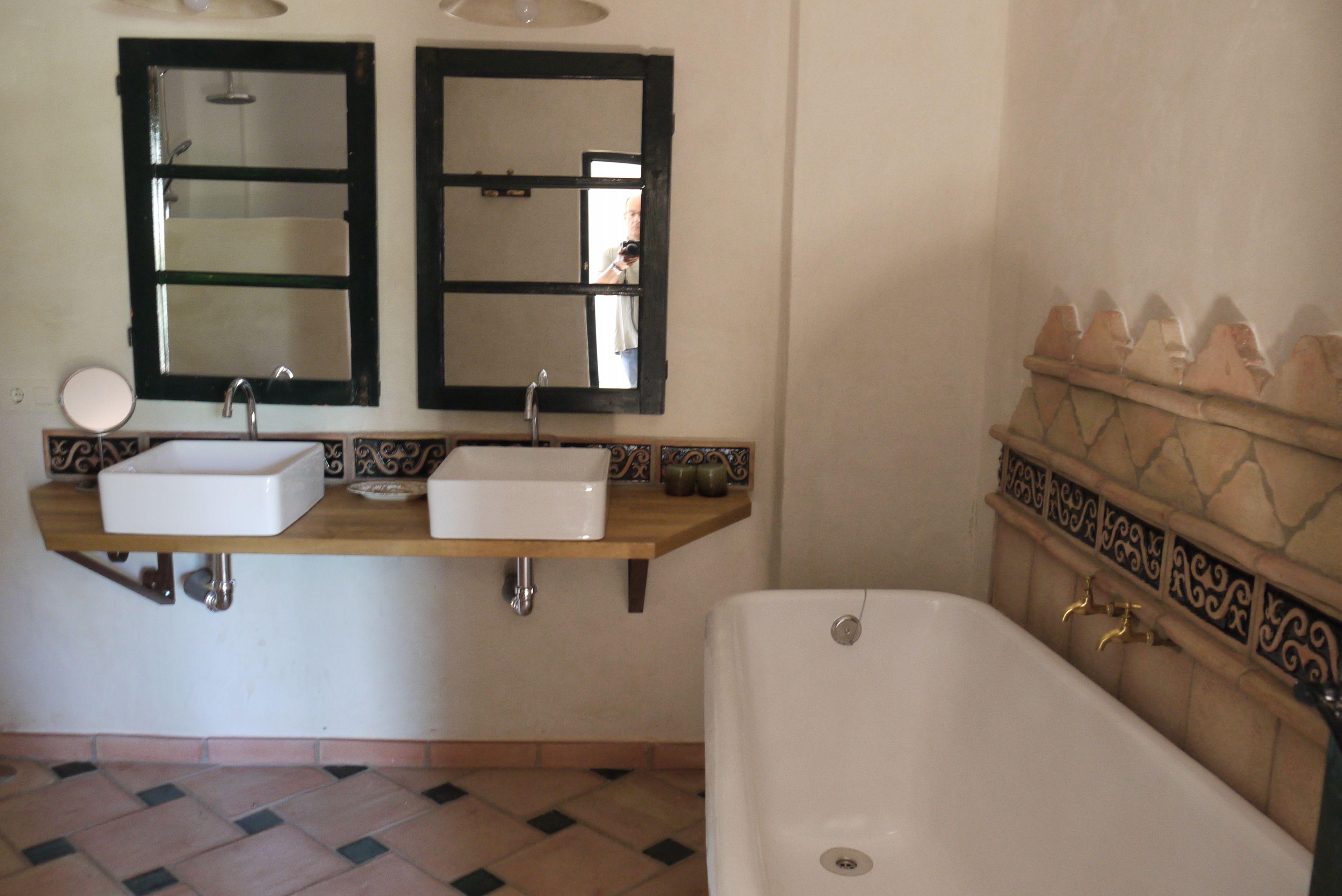Un baño con dos lavamanos, una bañera y azulejos decorativos.
