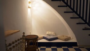 Un escalier avec un sol à carreaux, une chaise en bois et un petit coin salon avec des coussins.
