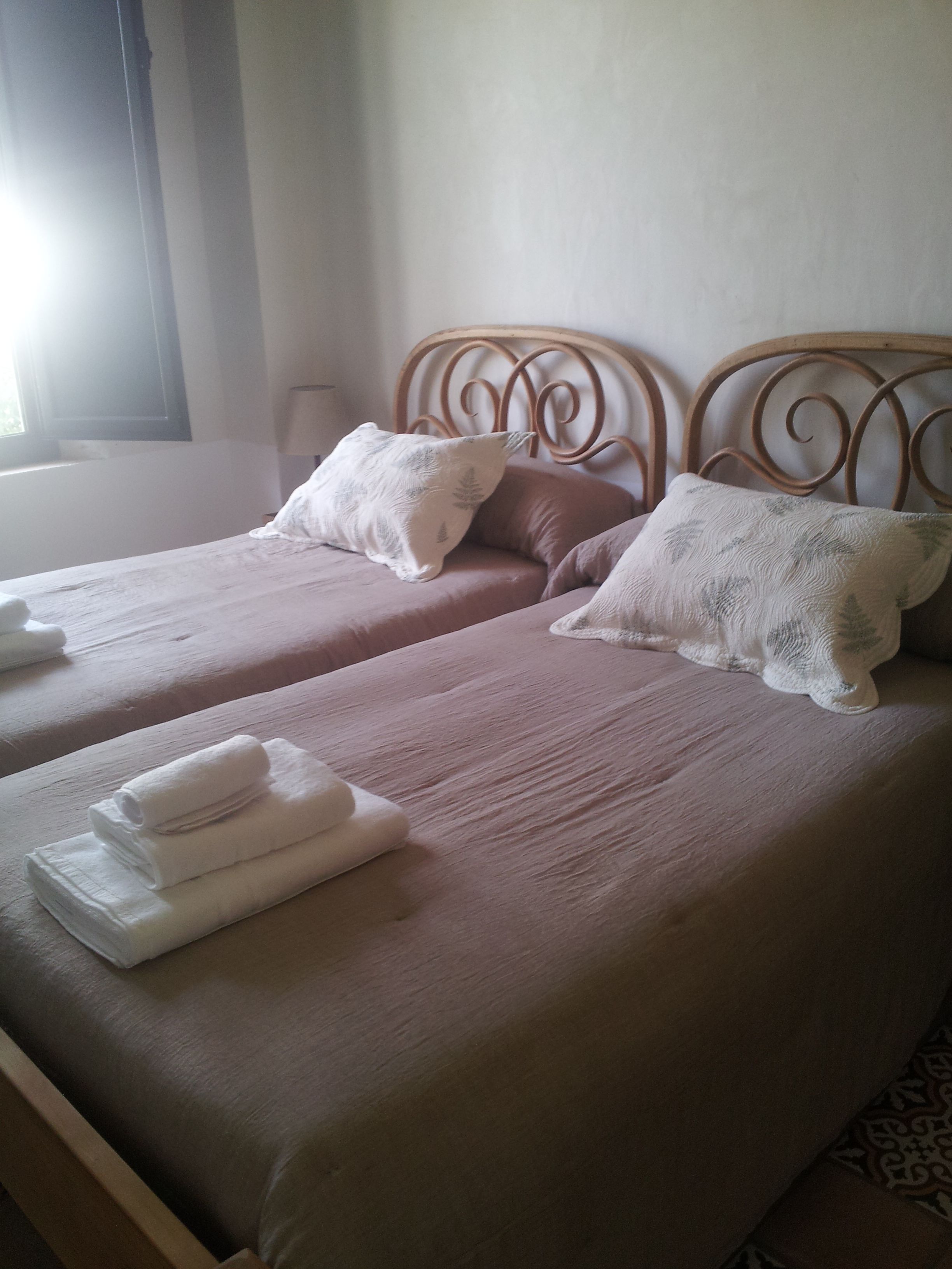 A double bed with two pillows and folded towels.