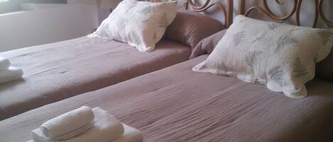 A double bed with two pillows and folded towels.