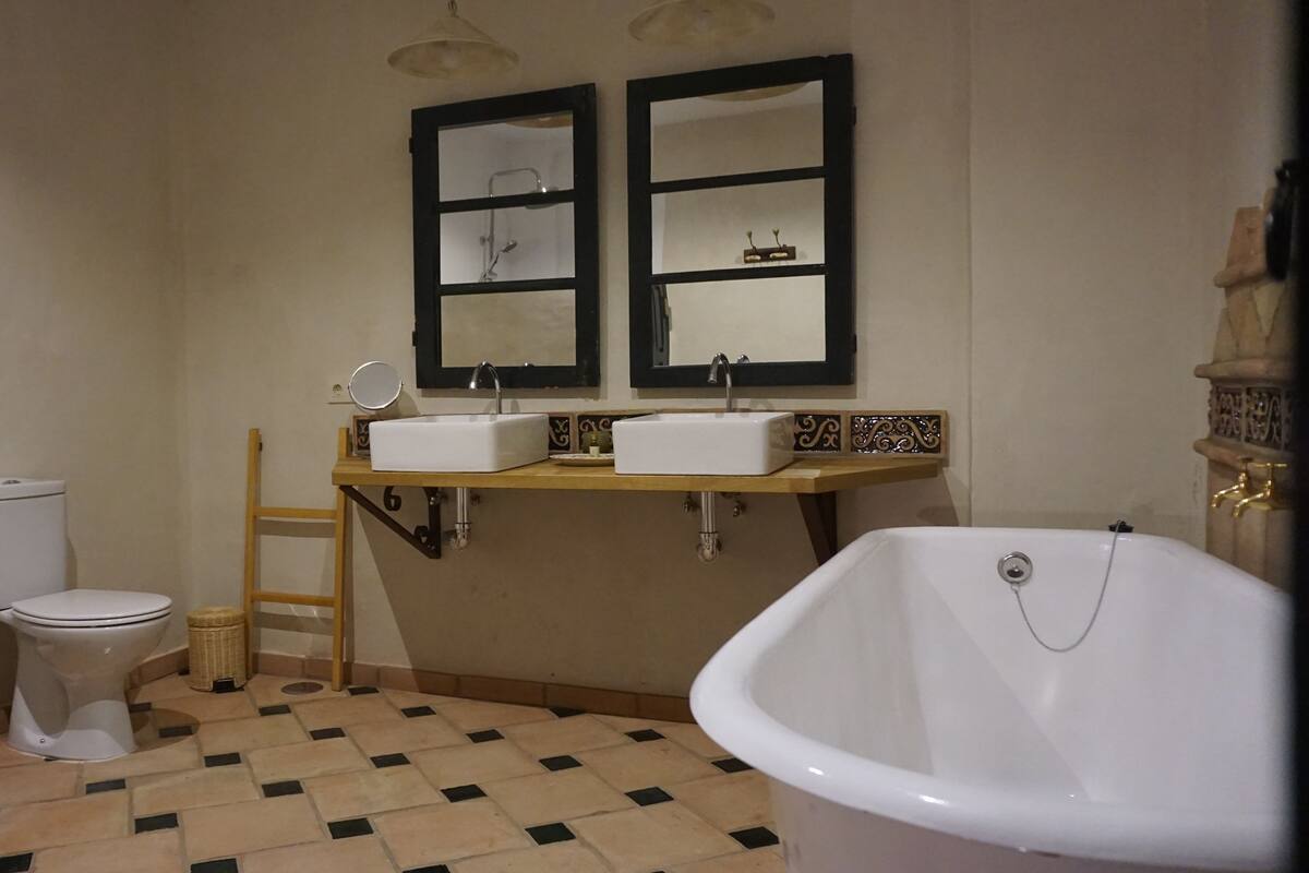Une salle de bain avec une baignoire, deux lavabos, des toilettes et un miroir.