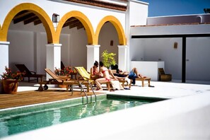 Un área junto a la piscina con sillones de descanso.