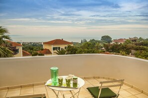 A balcony with a table, chairs, and a view of the surrounding landscape.