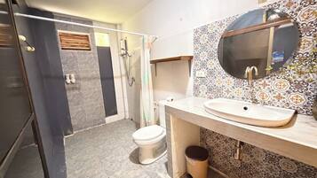 A bathroom with a shower, toilet, sink, and a mirror.