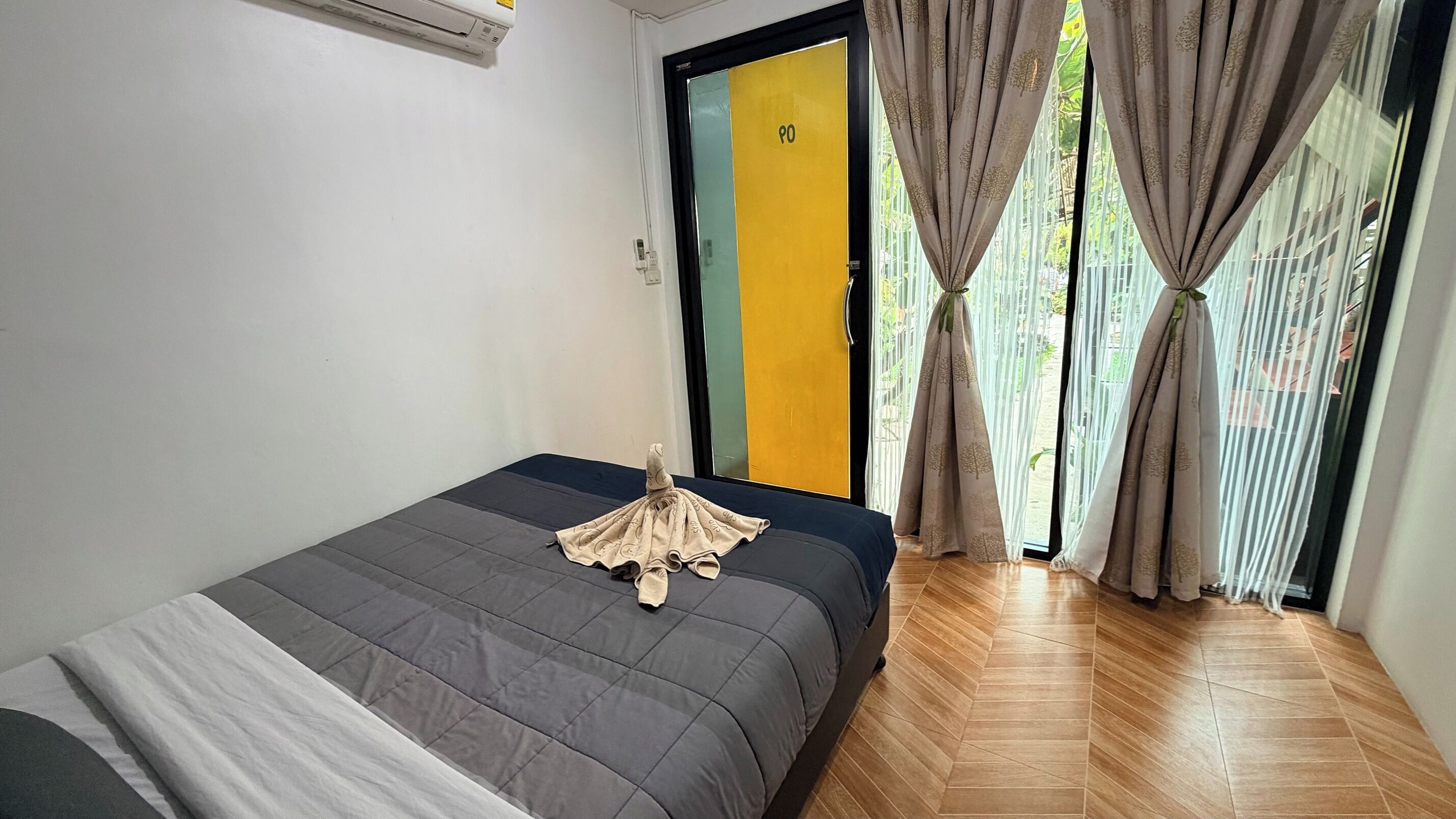 Een kamer met een bed, een deur met een nummer en gordijnen.