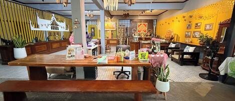 Una habitación amplia con una gran mesa de madera, diversas opciones de asiento y una variedad de objetos decorativos, incluyendo plantas y obras de arte.