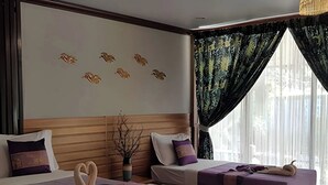 Una habitación de hotel con dos camas, un cabecero de madera, un adorno en la pared y un ventanal con cortinas translúcidas.