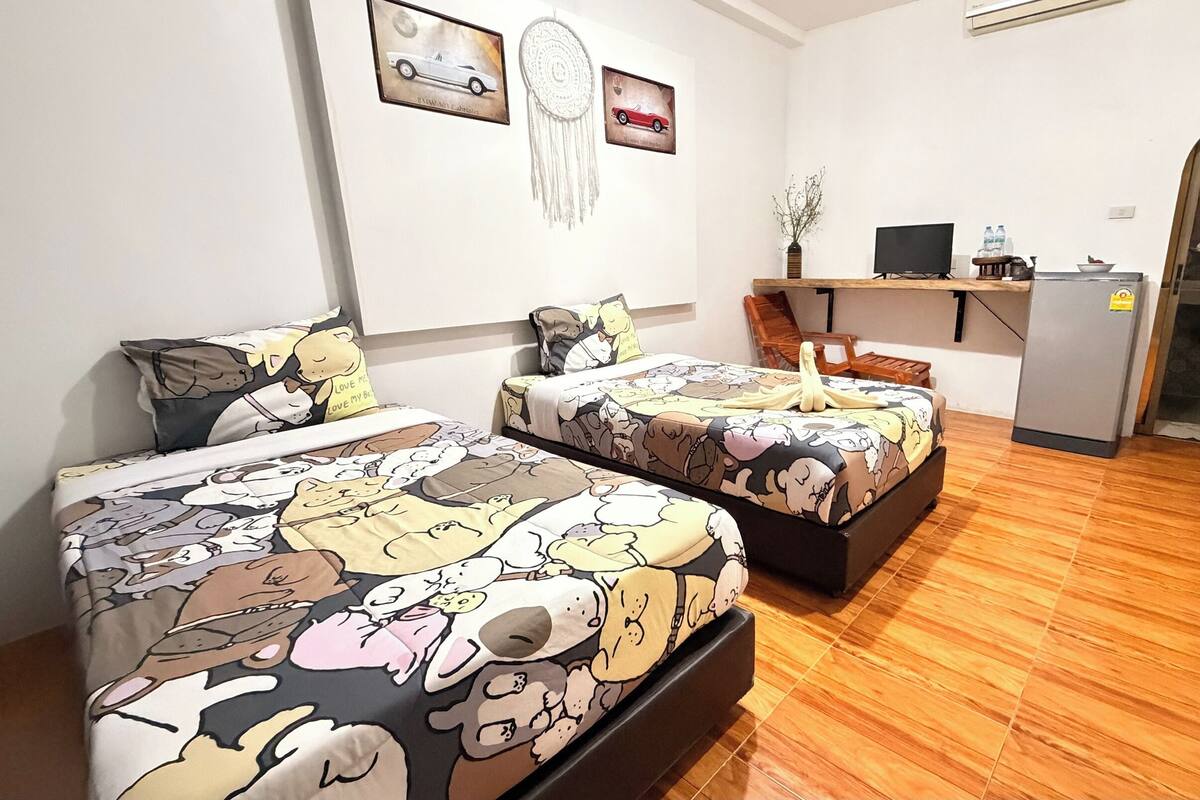 Una habitación con dos camas, un escritorio, un refrigerador y un espejo.