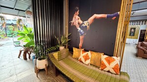 Una habitación con un sofá, plantas en macetas y un cartel grande.
