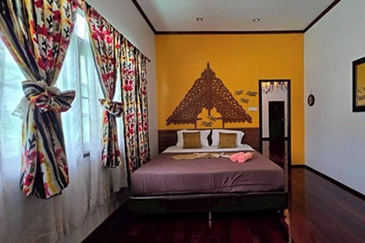 Un dormitorio con cama, cortinas, un cuadro en la pared y una puerta.