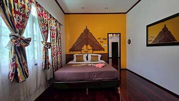 Un dormitorio con cama, cortinas, un cuadro en la pared y una puerta.