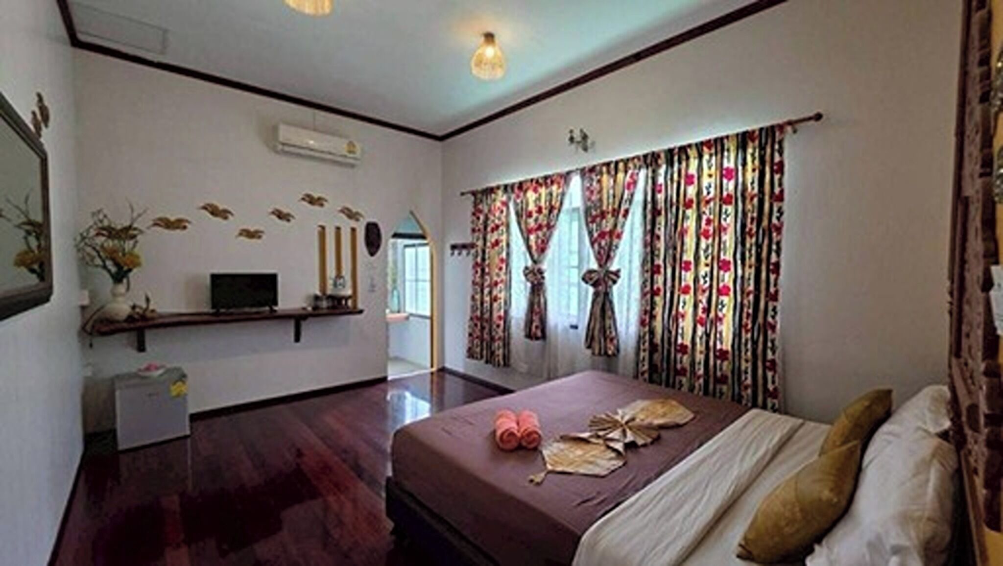 A hotel room with a bed, a television, a desk, and a window with curtains.