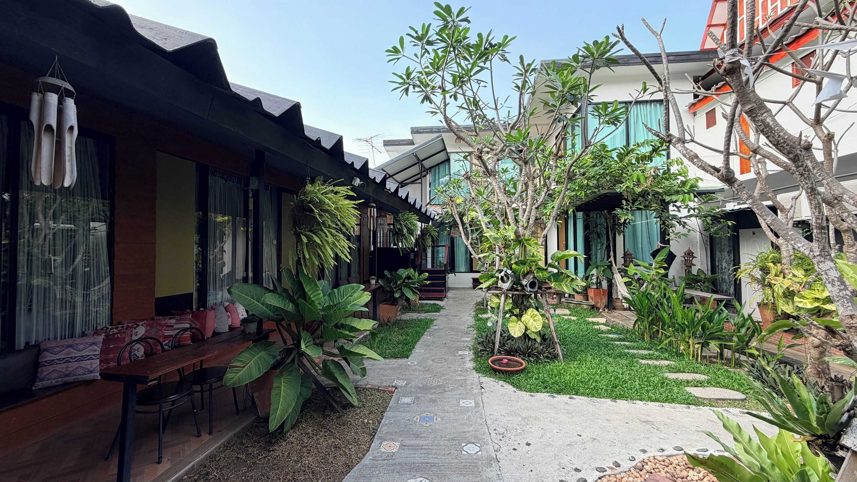 Un patio con un sendero, plantas en macetas y mobiliario para exterior.