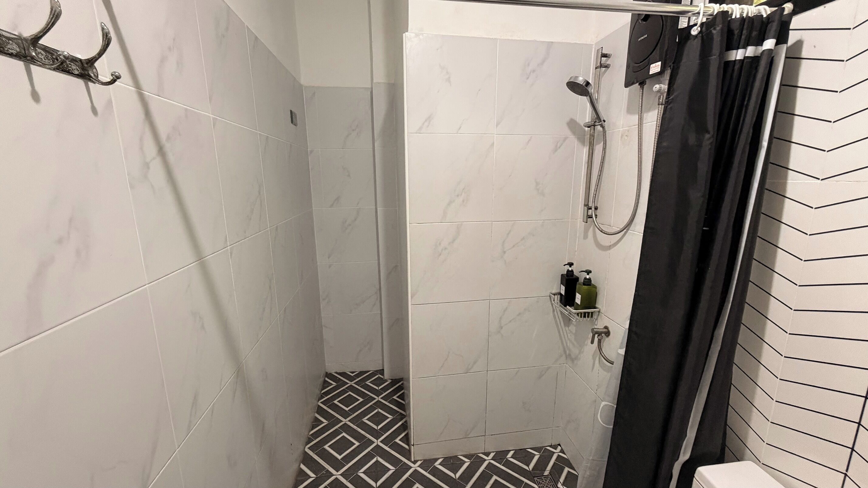A shower with a handheld showerhead, a handheld showerhead, and a shower caddy with toiletries.