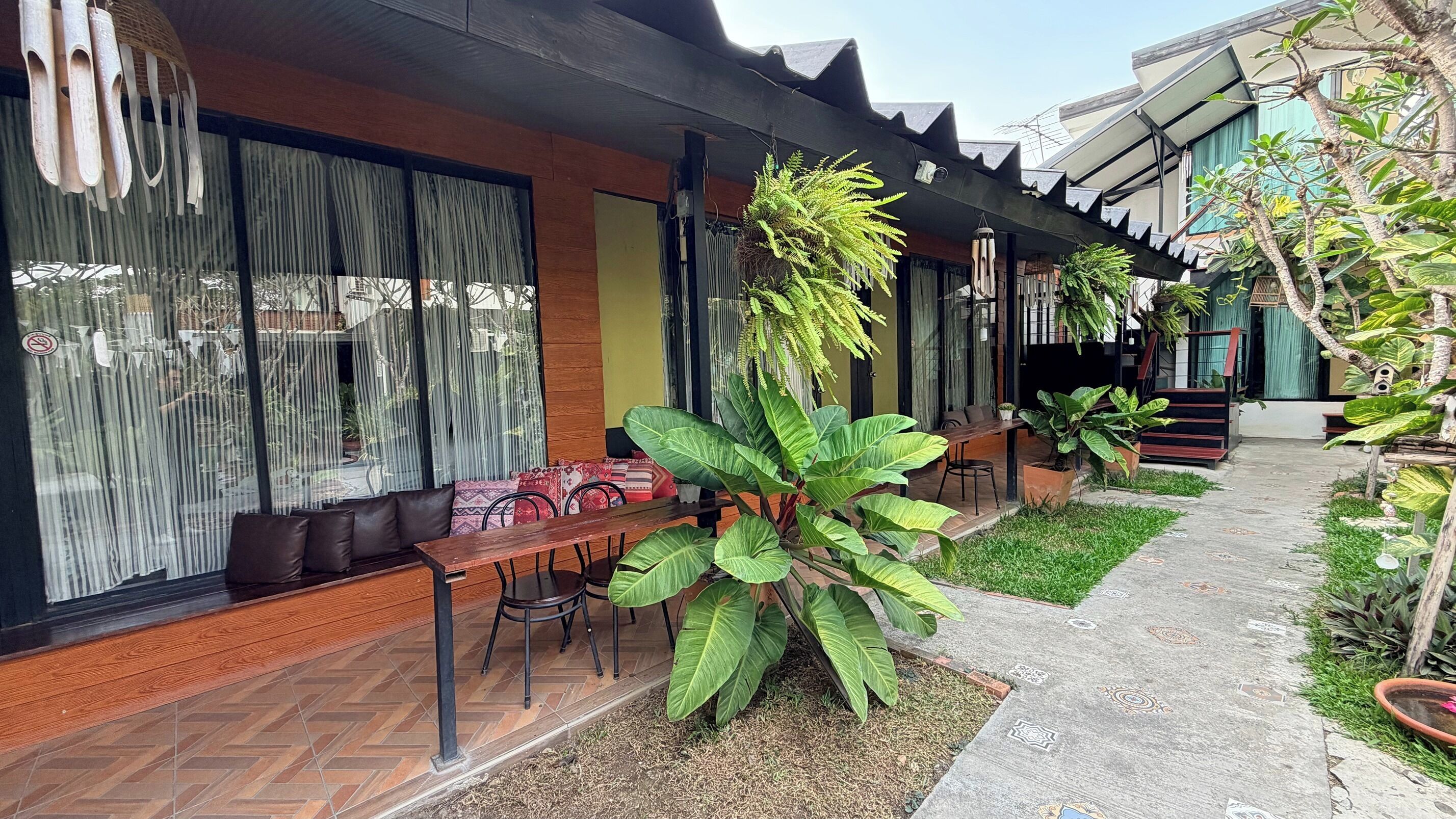 Un patio con un banco de madera, una mesa y plantas en macetas.