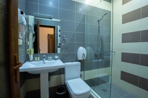 Een badkamer met een wit wastafelmeubel, toilet en douchecabine met glazen wanden.