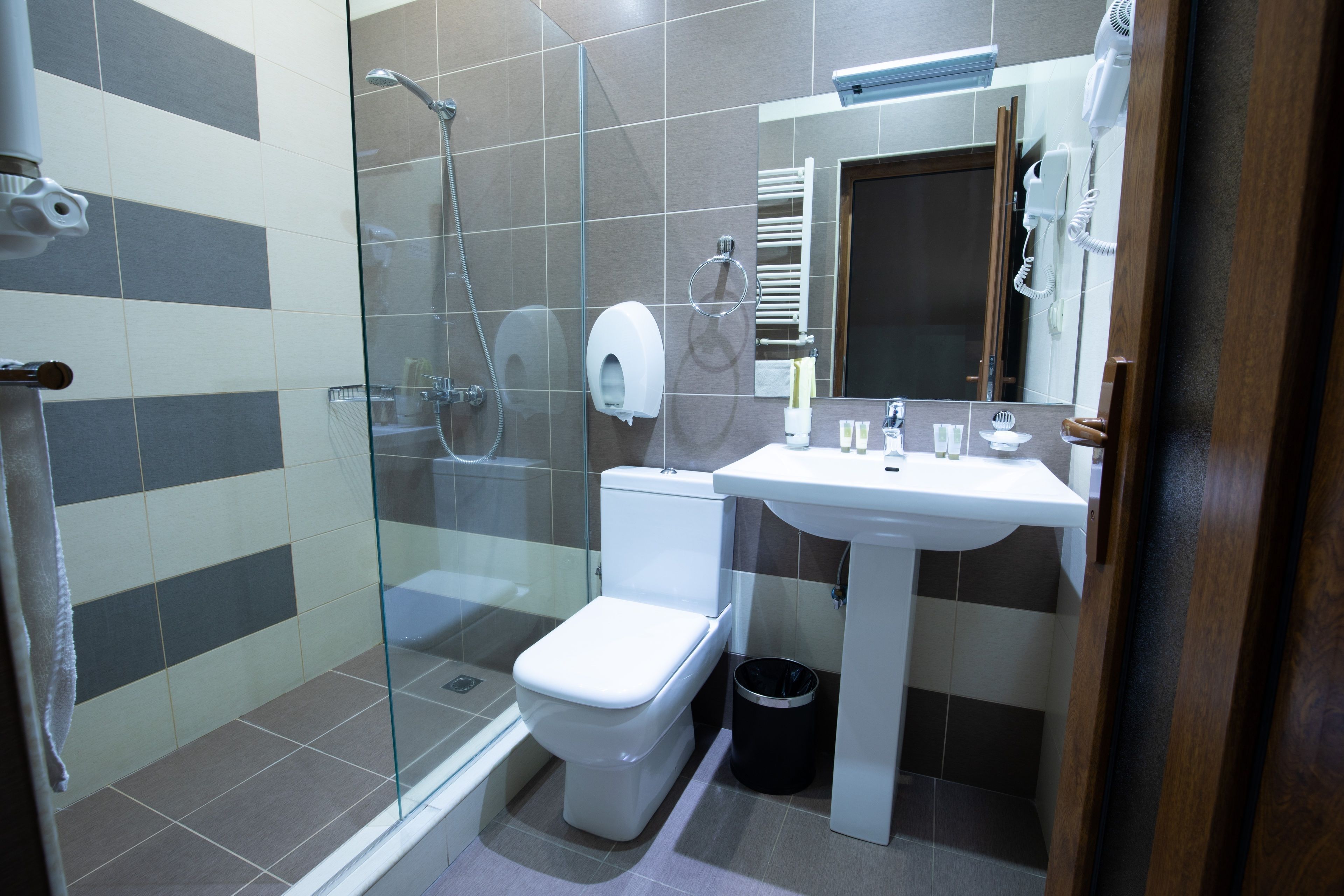 Une salle de bain moderne avec une douche à parois de verre, des toilettes blanches, un lavabo et un miroir.