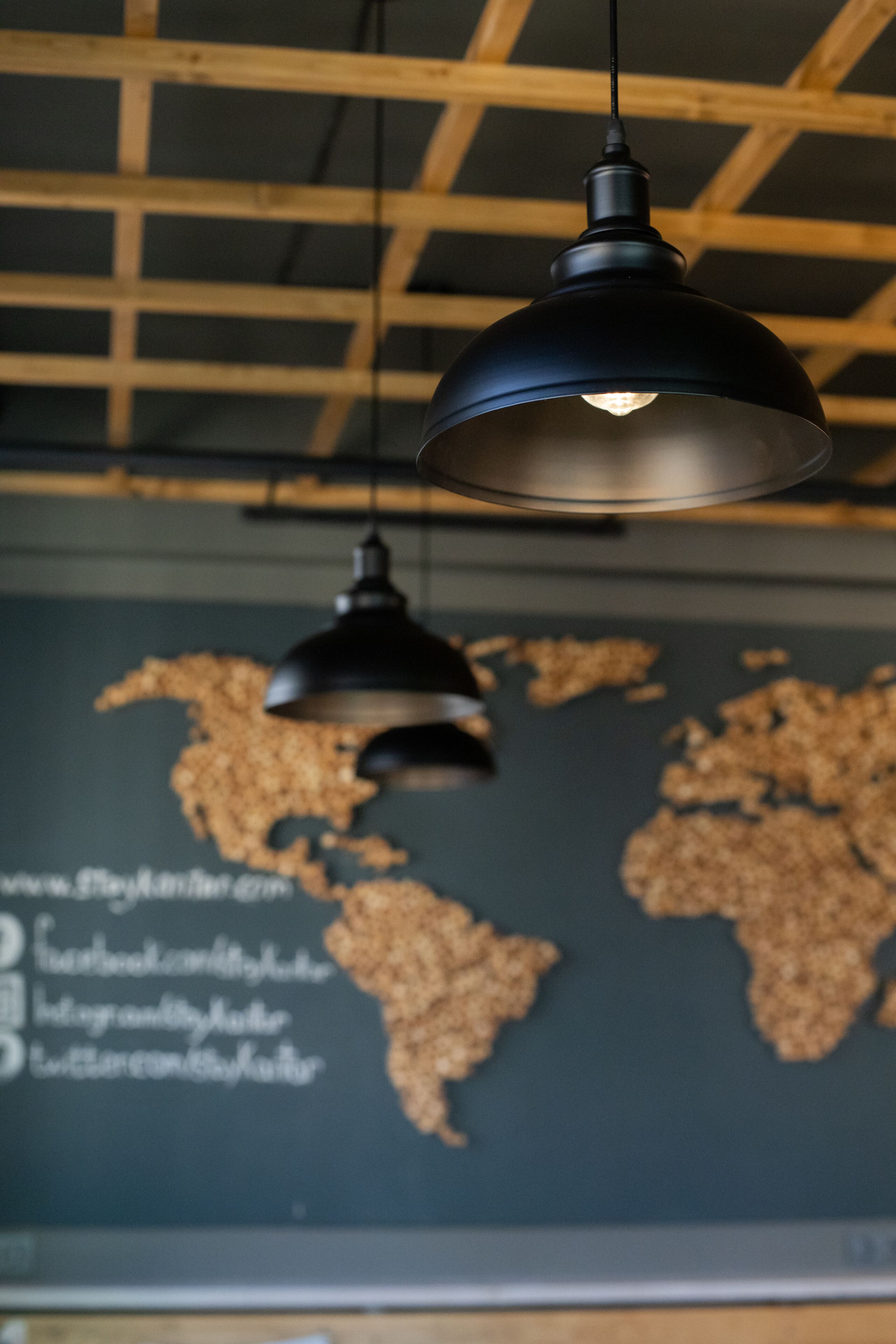 Een hangende, industriële pendellamp in een ruimte met een wereldkaart aan de muur.